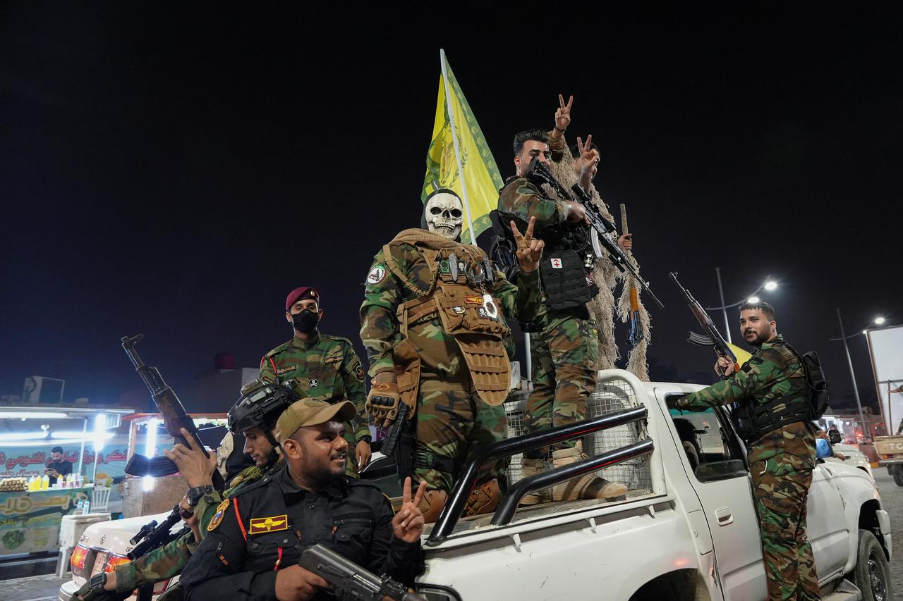 Iran-backed shi'ite groups fighters celebrate on a street, after the IRGC attack on Israel, in Basra