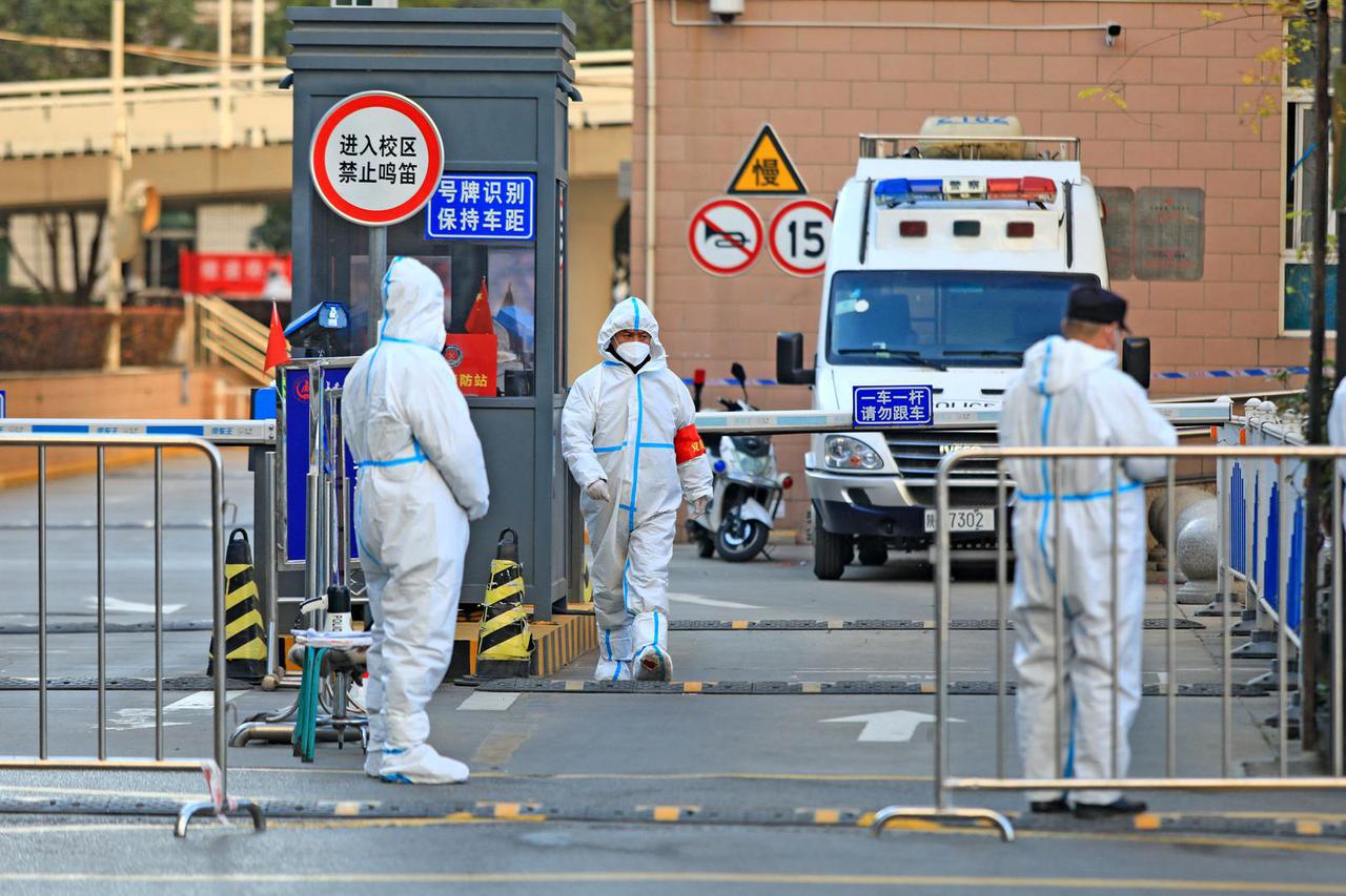 Workers stand at a residential area under lockdown following COVID-19 outbreak in Xian