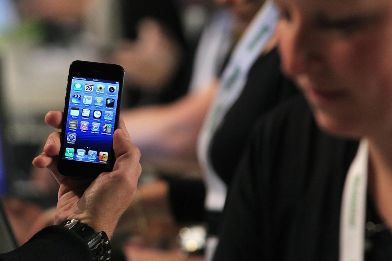 'A customer holds up an Apple iPhone 5 to pose for a photo during an exclusive sale by Belgian operator Mobistar in Brussels September 28, 2012. The iPhone 5 mobile phone is officially on sale in Belg