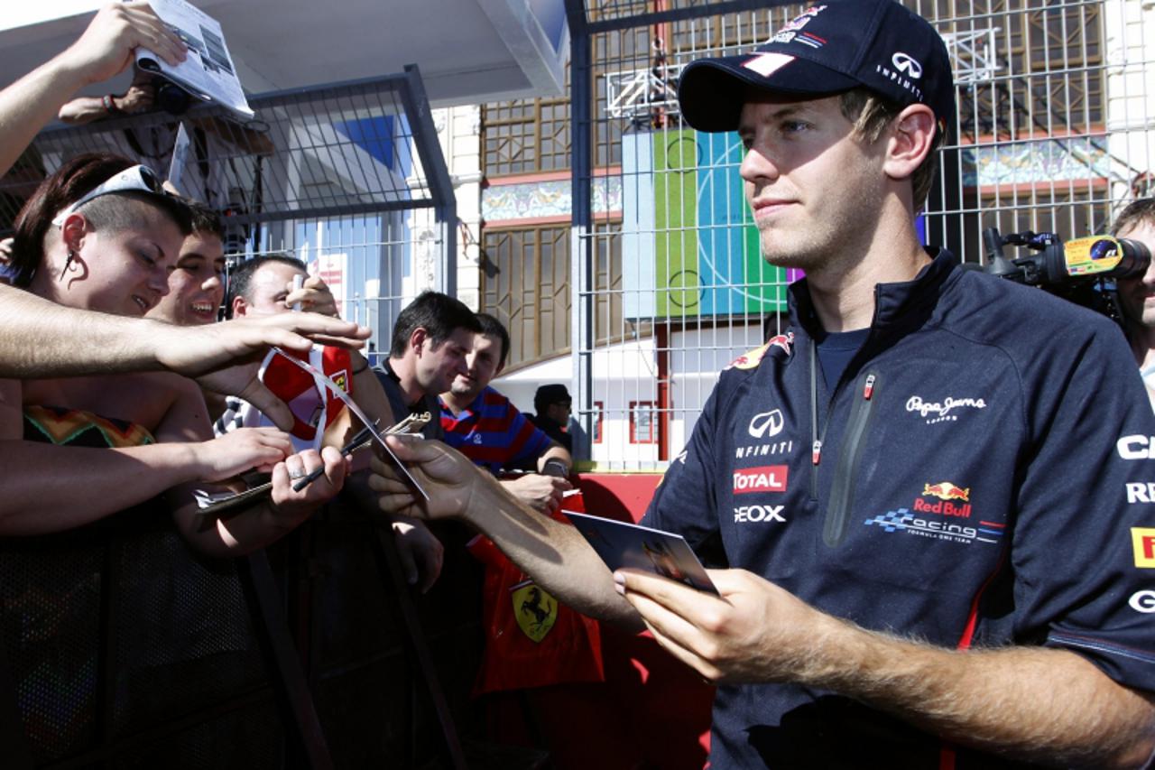 'Red Bull Formula One driver Sebastian Vettel of Germany signs autographs three days before the European F1 Grand Prix in Valencia June 21, 2012. REUTERS/Heino Kalis (SPAIN - Tags: SPORT MOTORSPORT)'