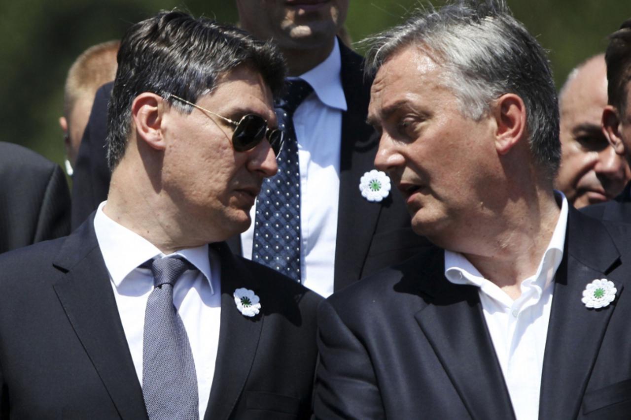 'Croatian Prime Minister Zoran Milanovic (L) speaks to Bosnian Foreign Affairs Minister Zlatko Lagumdzija during a ceremony at the Memorial Center in Potocari during a mass burial, near Srebrenica Jul