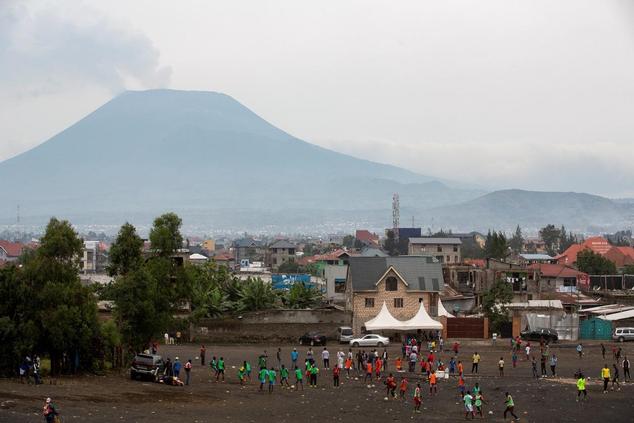 Congolese men play football with Mount Nyiragongo puffing away in the background, in Goma