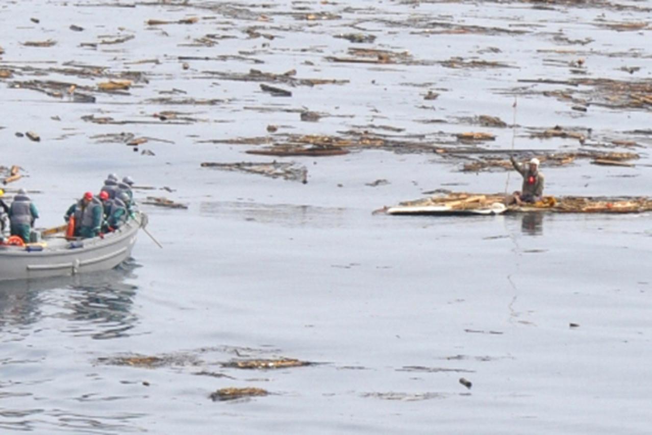 'Sixty-year-old survivor Hiromitsu Shinkawa (R) who was swept out to sea by a tsunami is seen as crew members of Japan Maritime Self-Defence Force (JMSDF) Aegis vessel Choukai approach to him for resc