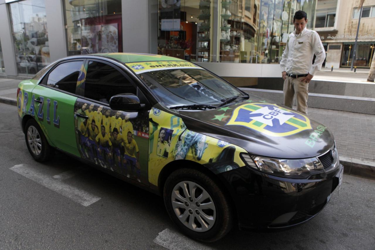 'A man stands near a car painted with an image of the Brazilian soccer team and the logo of the Brazilian Football Confederation in Beirut June 16, 2010, in support of the team in the World Cup in Sou