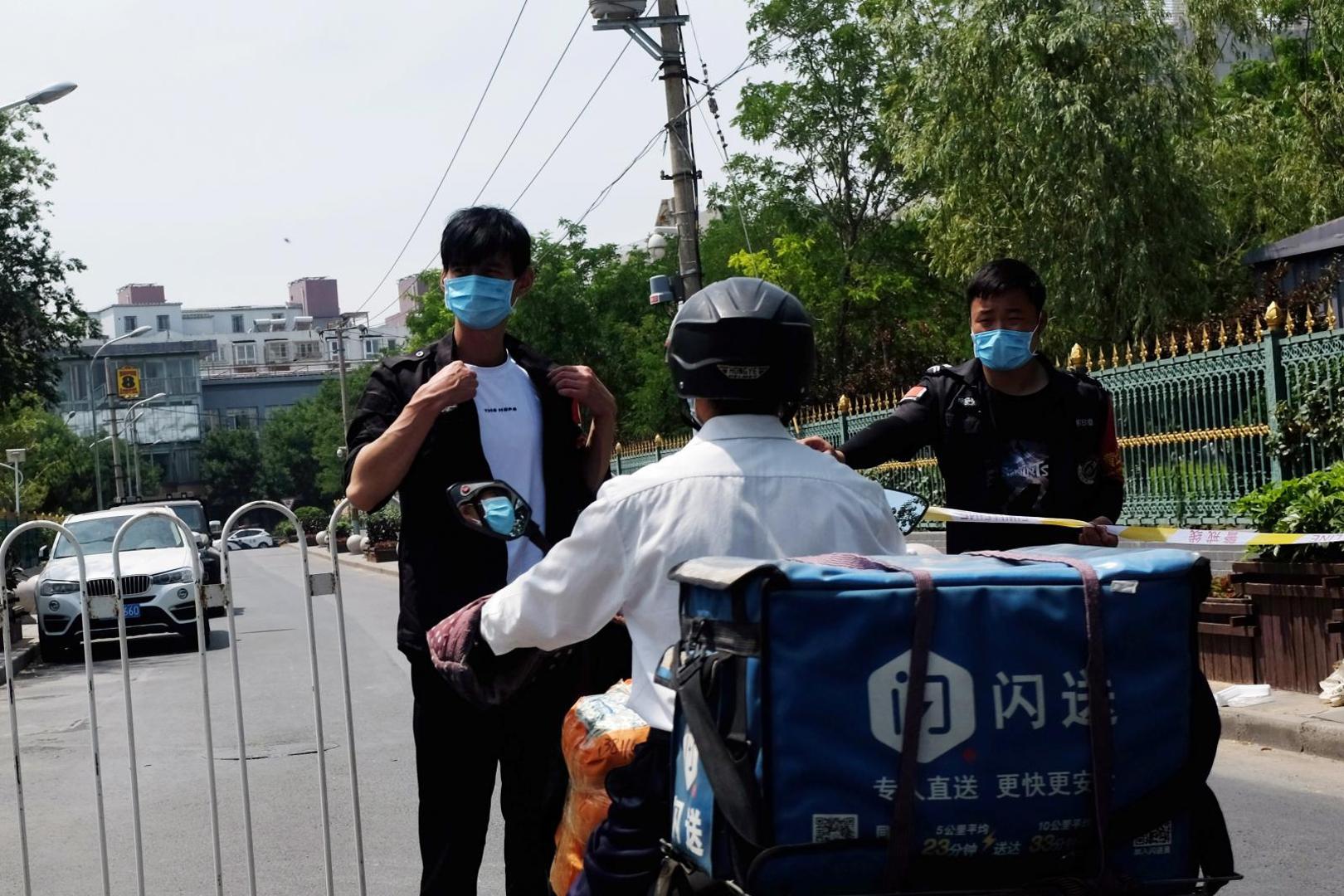 Security personnel and a delivery worker are seen at an entrance to a residential area in Beijing Security personnel and a delivery worker are seen at an entrance to a residential area under lockdown near the Xinfadi wholesale market, following cases of the coronavirus disease (COVID-19) infections, in Beijing, China June 16, 2020.  REUTERS/Tingshu Wang TINGSHU WANG