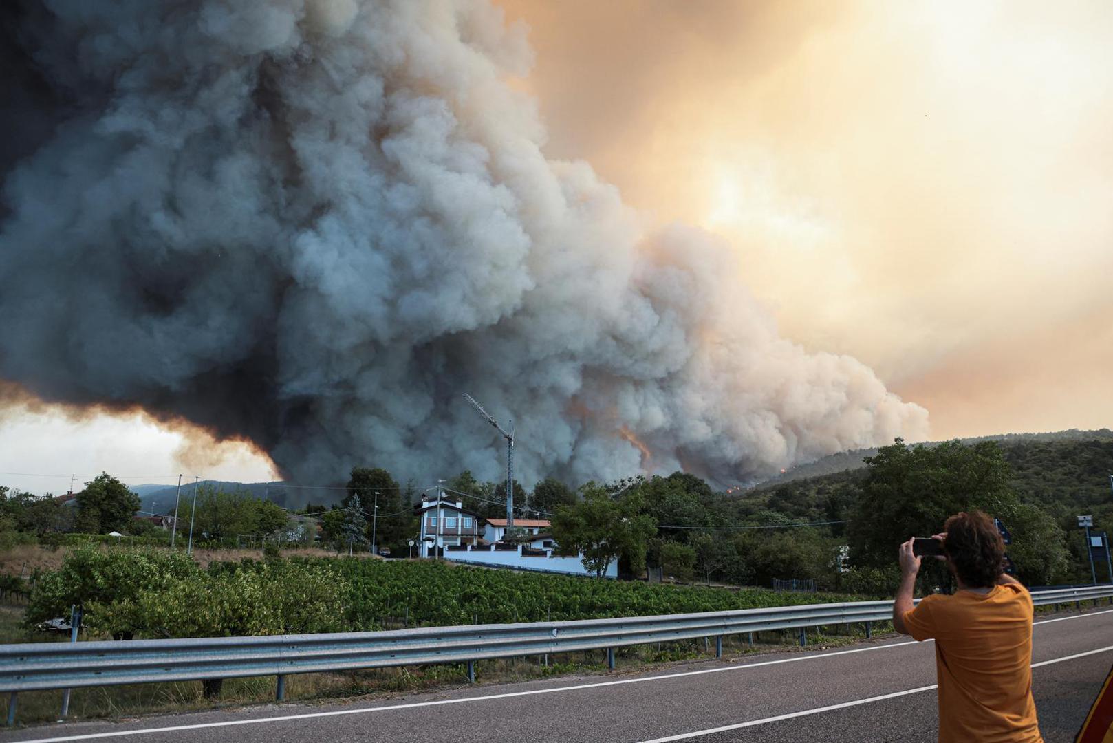 A person records as smoke billows from a wildfire at the border with Slovenia seen from Rupa, Italy, July 20, 2022. REUTERS/Borut Zivulovic Photo: BORUT ZIVULOVIC/REUTERS