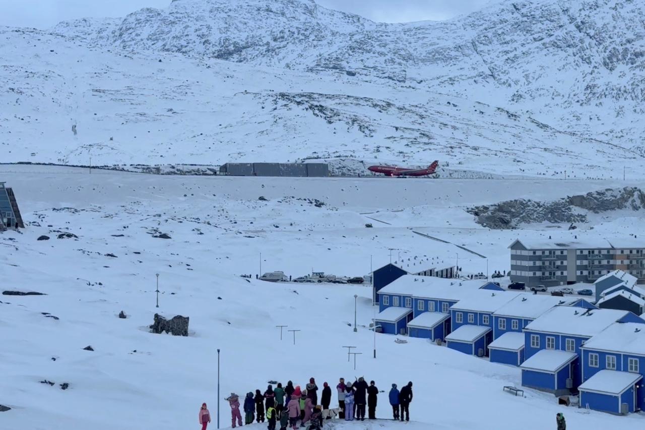 People look as a plane lands on the day the expansion of Nuuk's International Airport is inaugurated with a flight from Copenhagen