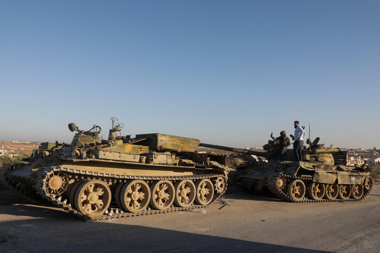 Men stand on a military vehicle in the city of Maarat al-Numan, in Idlib province