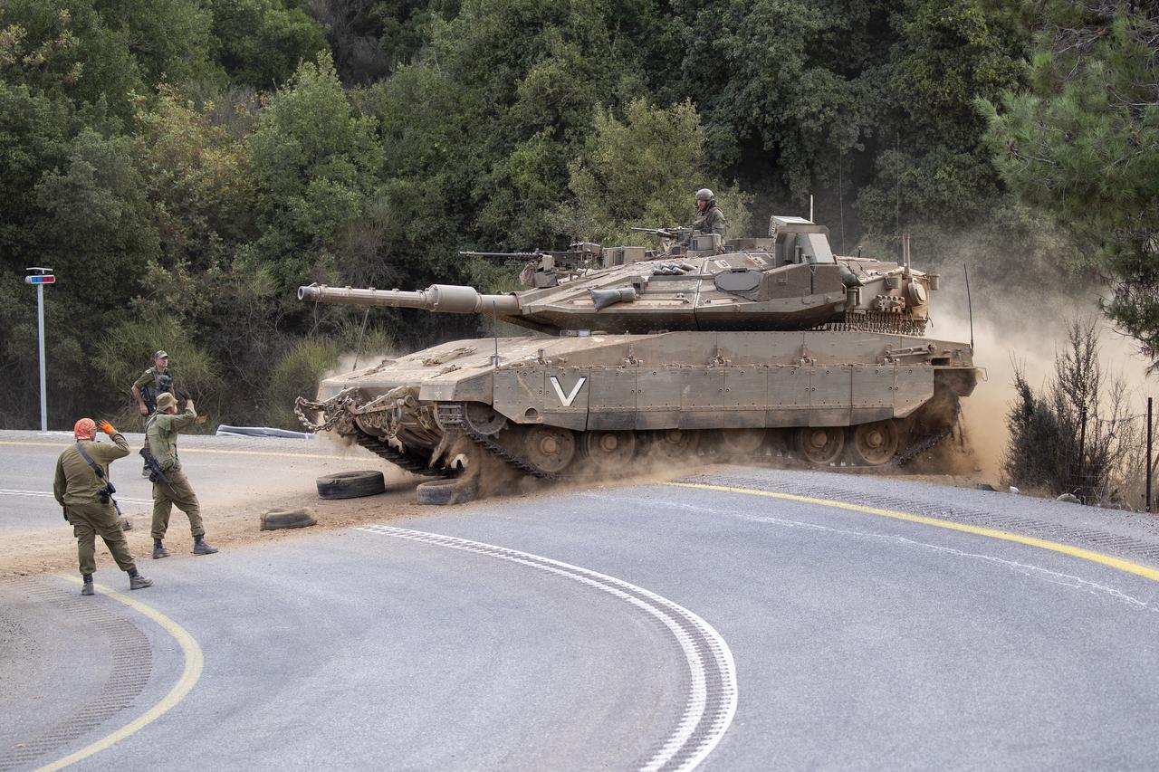 An Israeli tank at an undisclosed location in northern Israel crosses a road as a column of Israeli tanks and armored personnel carriers (APCs) make their way into southern Lebanon during ground operations on October 1, 2024.