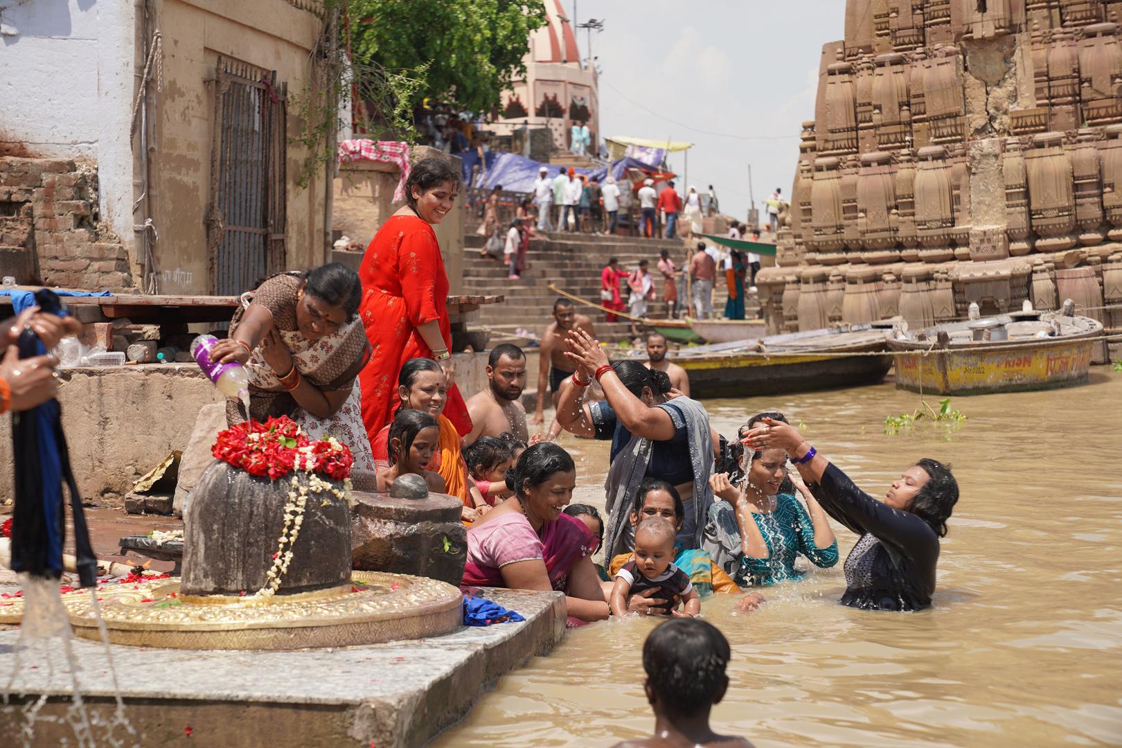 19 July 2024, India, Varanasi: People bathe next to a symbol of the god Shiva in the Ganges after they have also immersed the ashes of their loved ones there. Shiva is the most important deity of Varanasi. Photo: Anne-Sophie Galli/dpa Photo: Anne-Sophie Galli/DPA