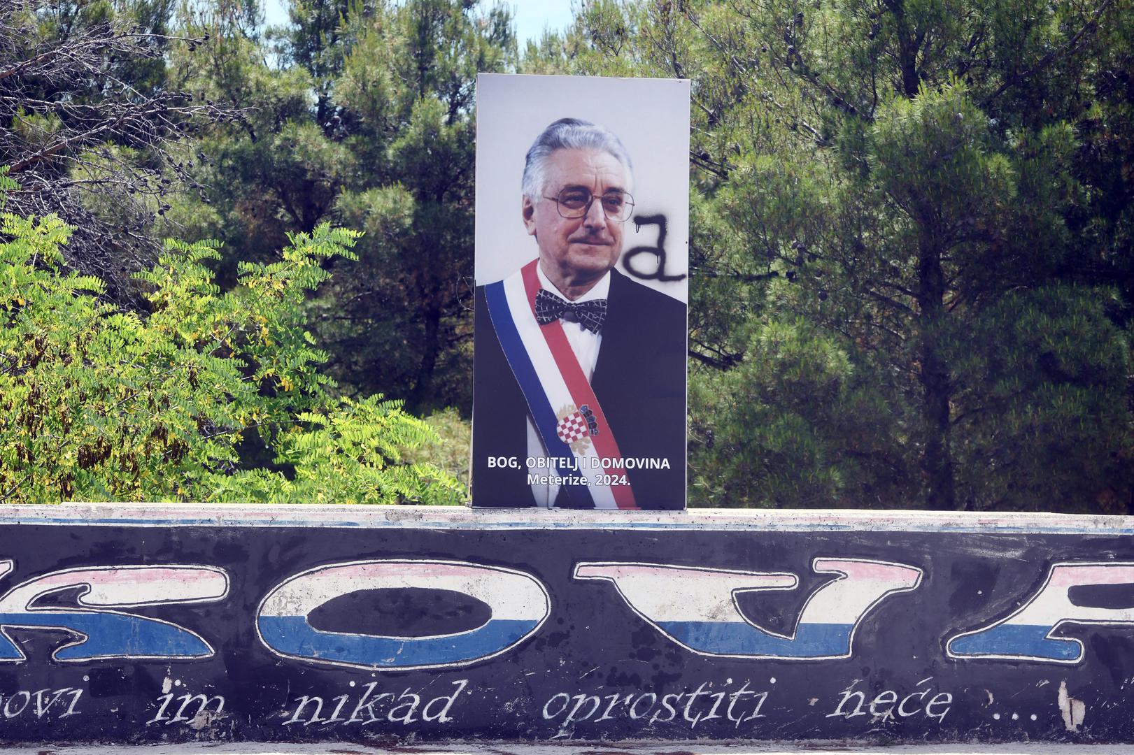 Plakat se nalazi pored ceste, na zidu na kojem je iscrtan mural posvećen Vukovaru. "Grobovi im nikad oprostiti neće", piše na muralu.