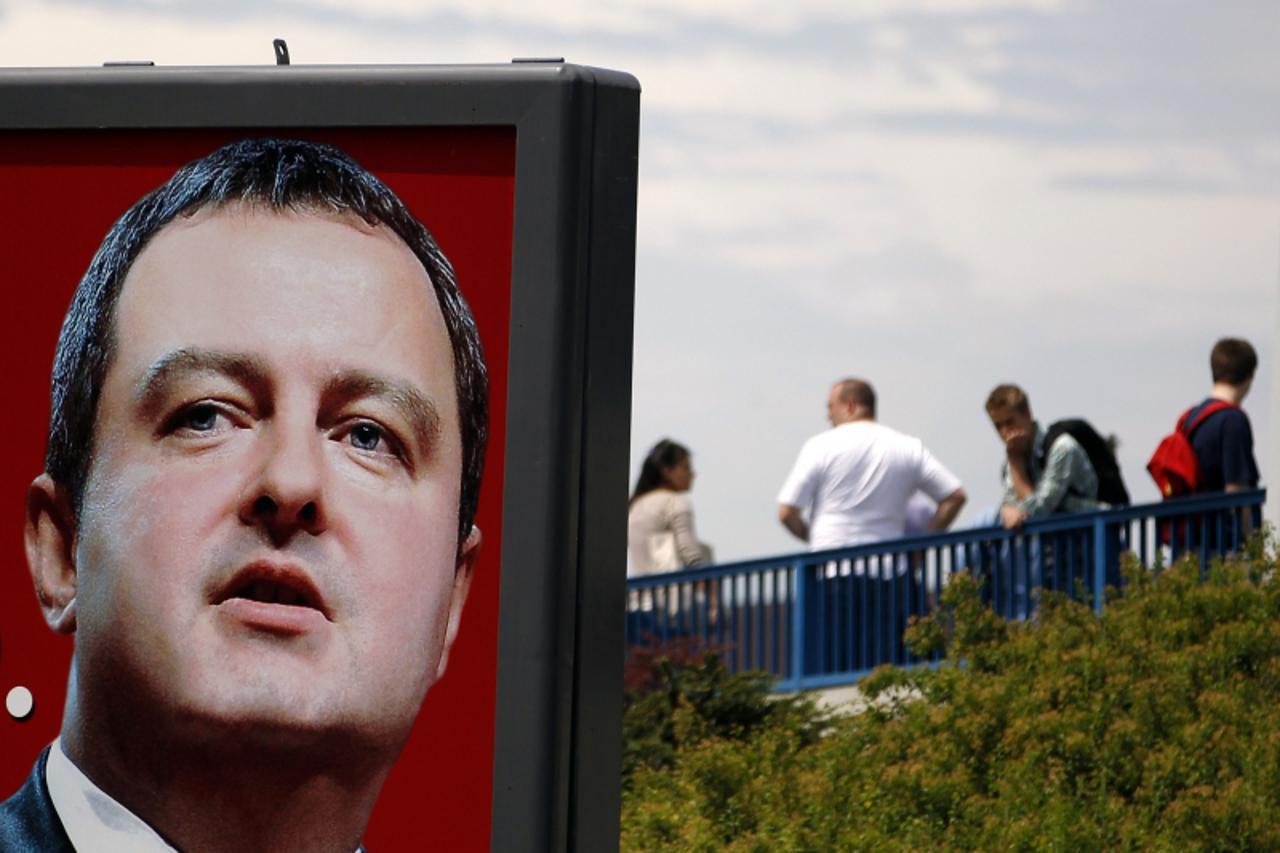 'People wait for a bus near a pre-election billboard of the Socialist party leader Ivica Dacic in Belgrade May 7, 2012. The Socialist Party of late strongman Slobodan Milosevic held the key to power i