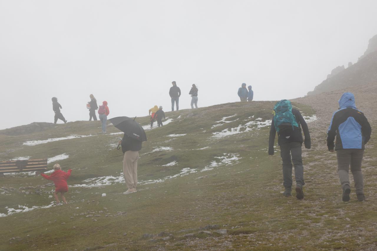 Tourists walk next to fresh snow on Mount Hafelekar near Innsbruck