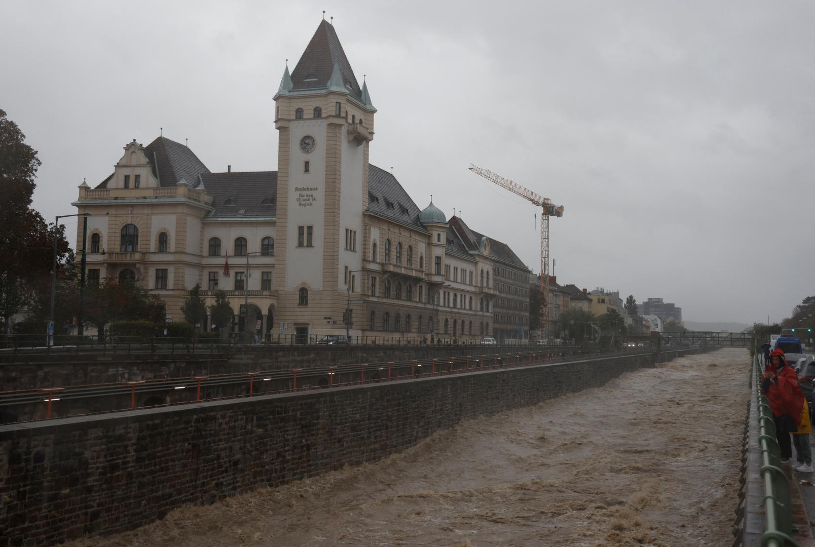 A person holding a smartphone stands next to the flooded Wienfluss river channel during heavy rain, after Austrian forecasters expanded a warning for extreme rainfall to areas of the country including the capital, in Vienna, Austria, September 15, 2024. REUTERS/Leonhard Foeger Photo: LEONHARD FOEGER/REUTERS