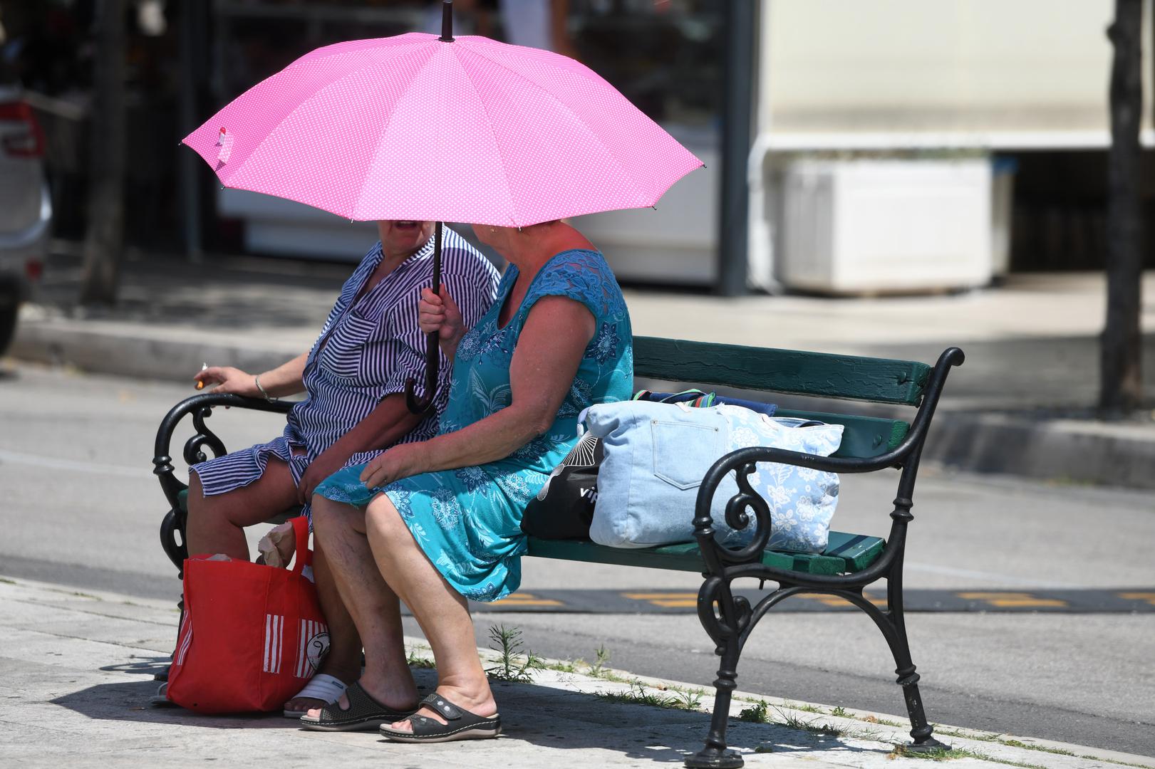 07.07.2023., Sibenik - Zastitu od sunca gospodje potrazile pod kisobranom. Najavu toplinskog udara shvatile su ozbiijno. Photo: Hrvoje Jelavic/PIXSELL