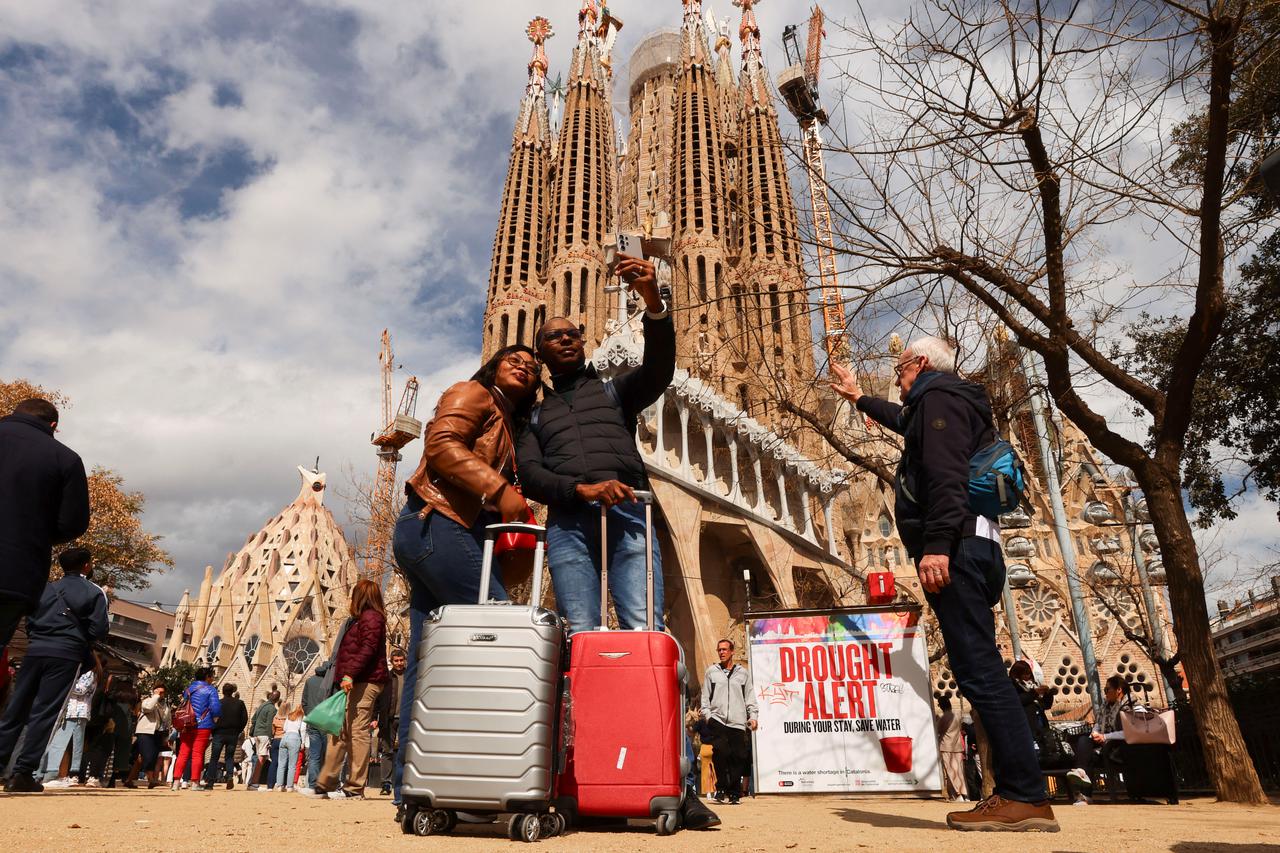 Tourists take a selfie next to a sign at the Sagrada Familia Basilica in Barcelona