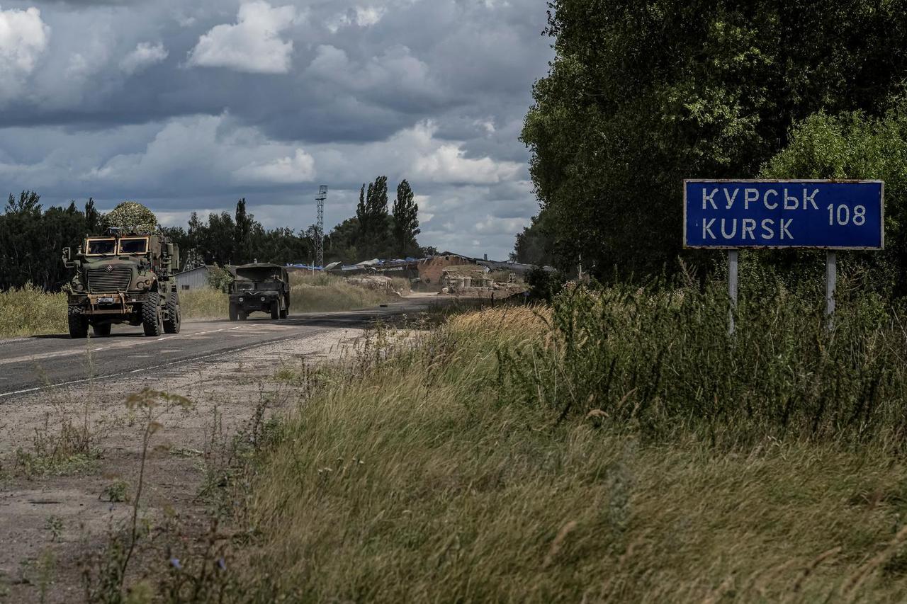 Ukrainian servicemen ride military vehicles from a crossing point at the border with Russia in Sumy region