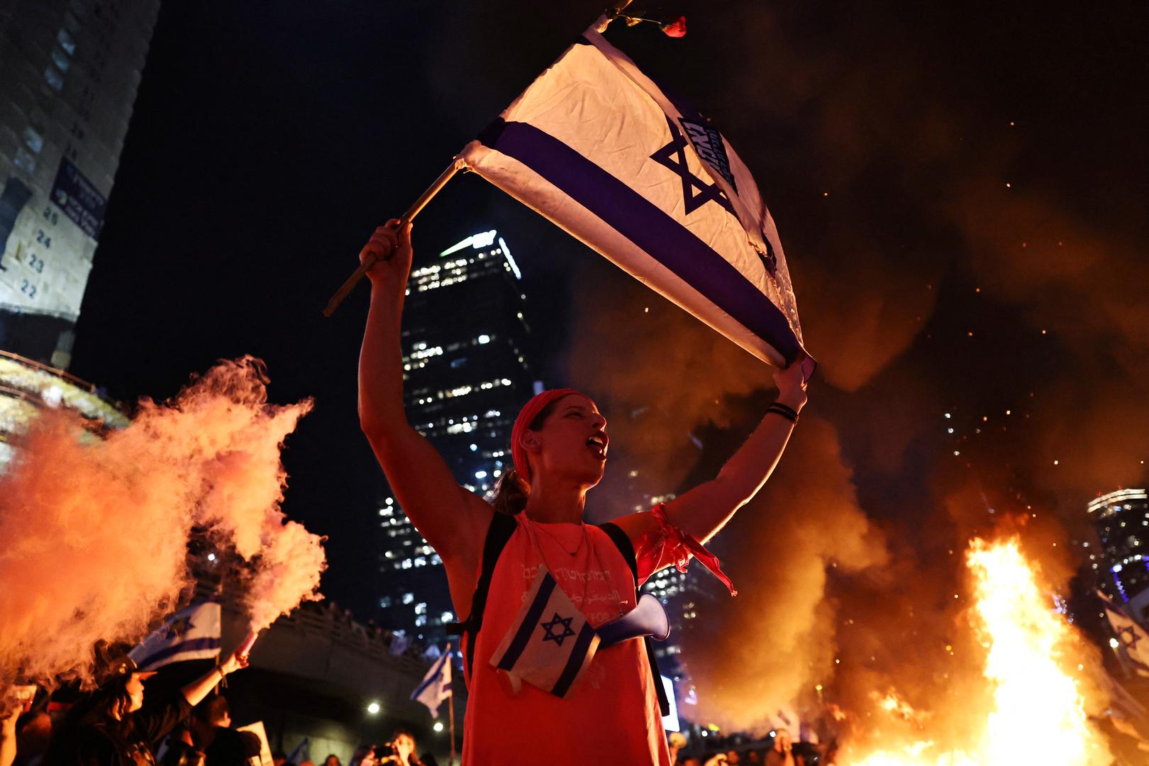 A person holds an Israeli flag as people demonstrate after Israeli Prime Minister Benjamin Netanyahu sacked his defense minister, Yoav Gallant, citing lack of trust, in Tel Aviv, Israel November 5, 2024. REUTERS/Thomas Peter Photo: Thomas Peter/REUTERS