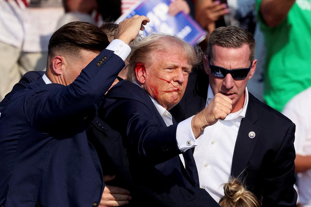 Republican presidential candidate and former U.S. President Donald Trump gestures as he is assisted by the Secret Service after gunfire rang out during a campaign rally at the Butler Farm Show in Butler.