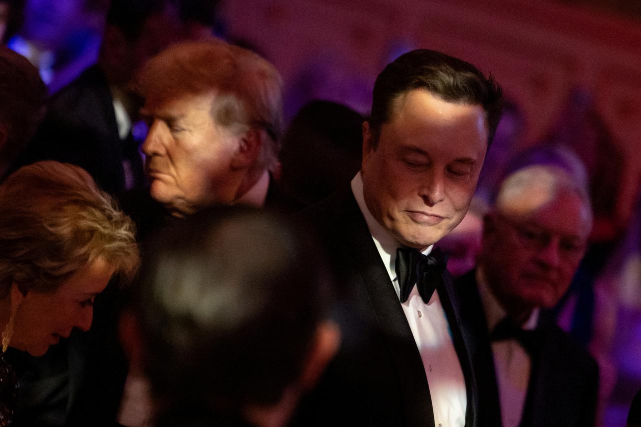 FILE PHOTO: U.S. President-elect Donald Trump walks by Elon Musk during the America First Policy Institute (AFPI) gala at Mar-A-Lago in Palm Beach, Florida