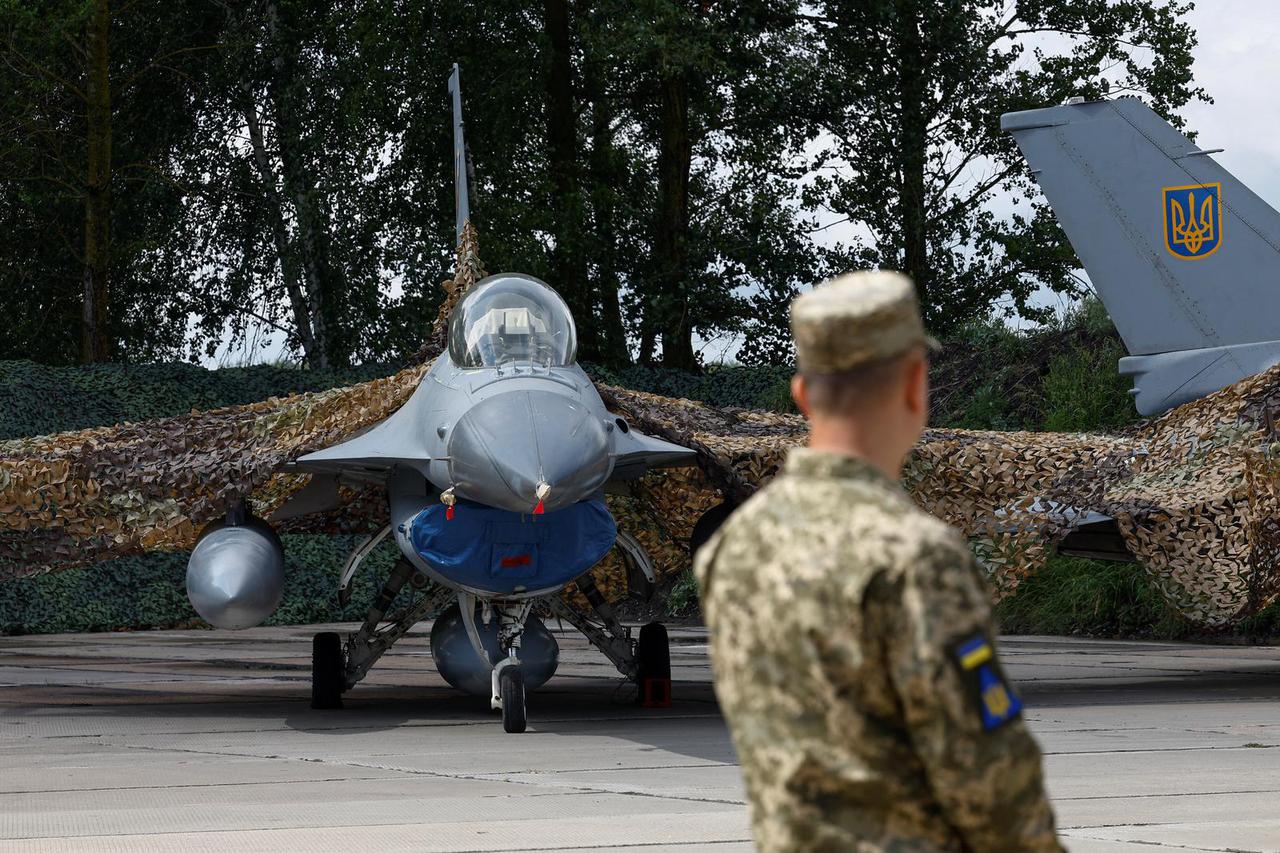 Ukrainian serviceman stands next to an F-16 fighting aircraft in an undisclosed location in Ukraine