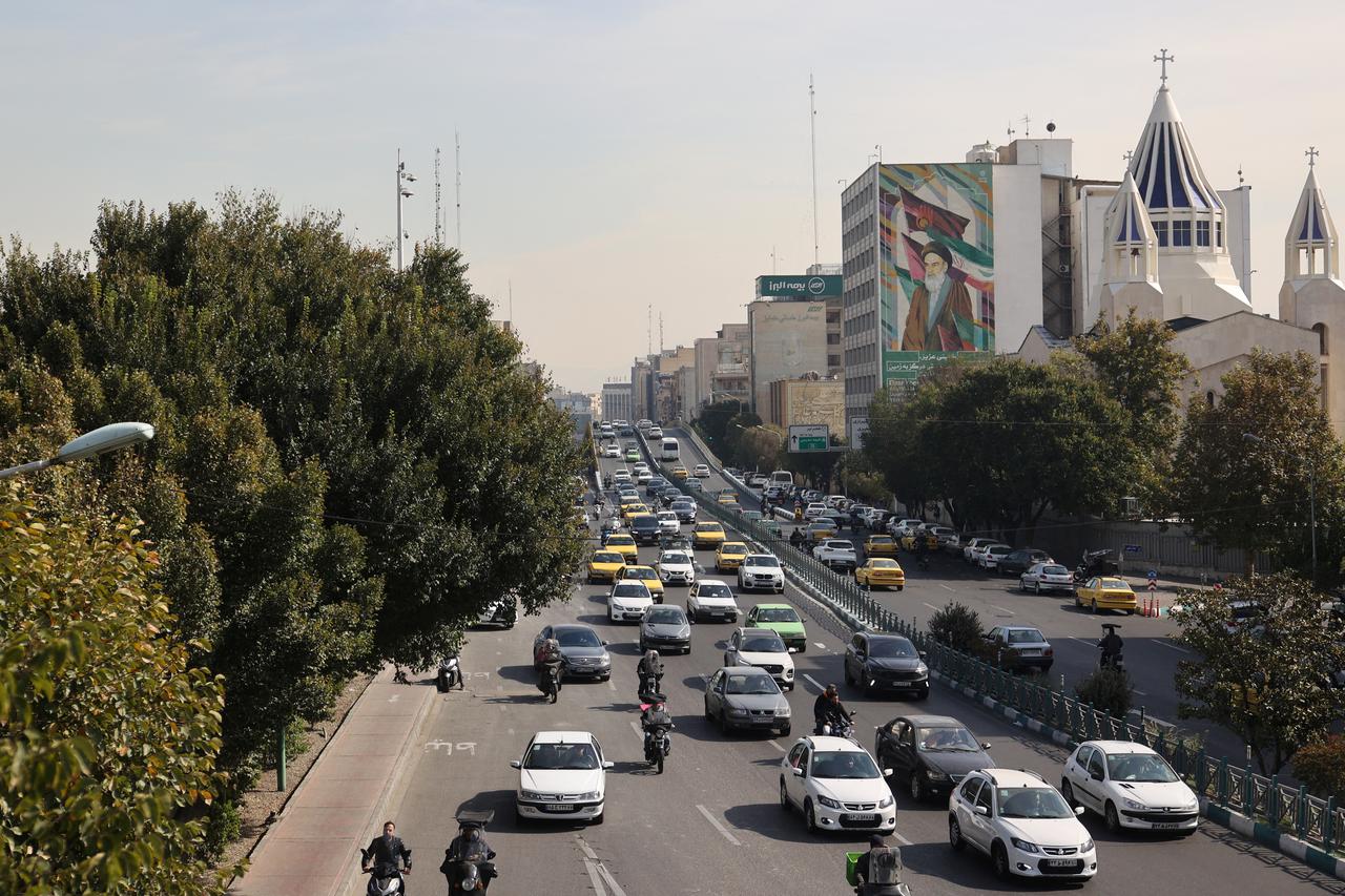 Cars pass on a street after several explosions were heard, in Tehran