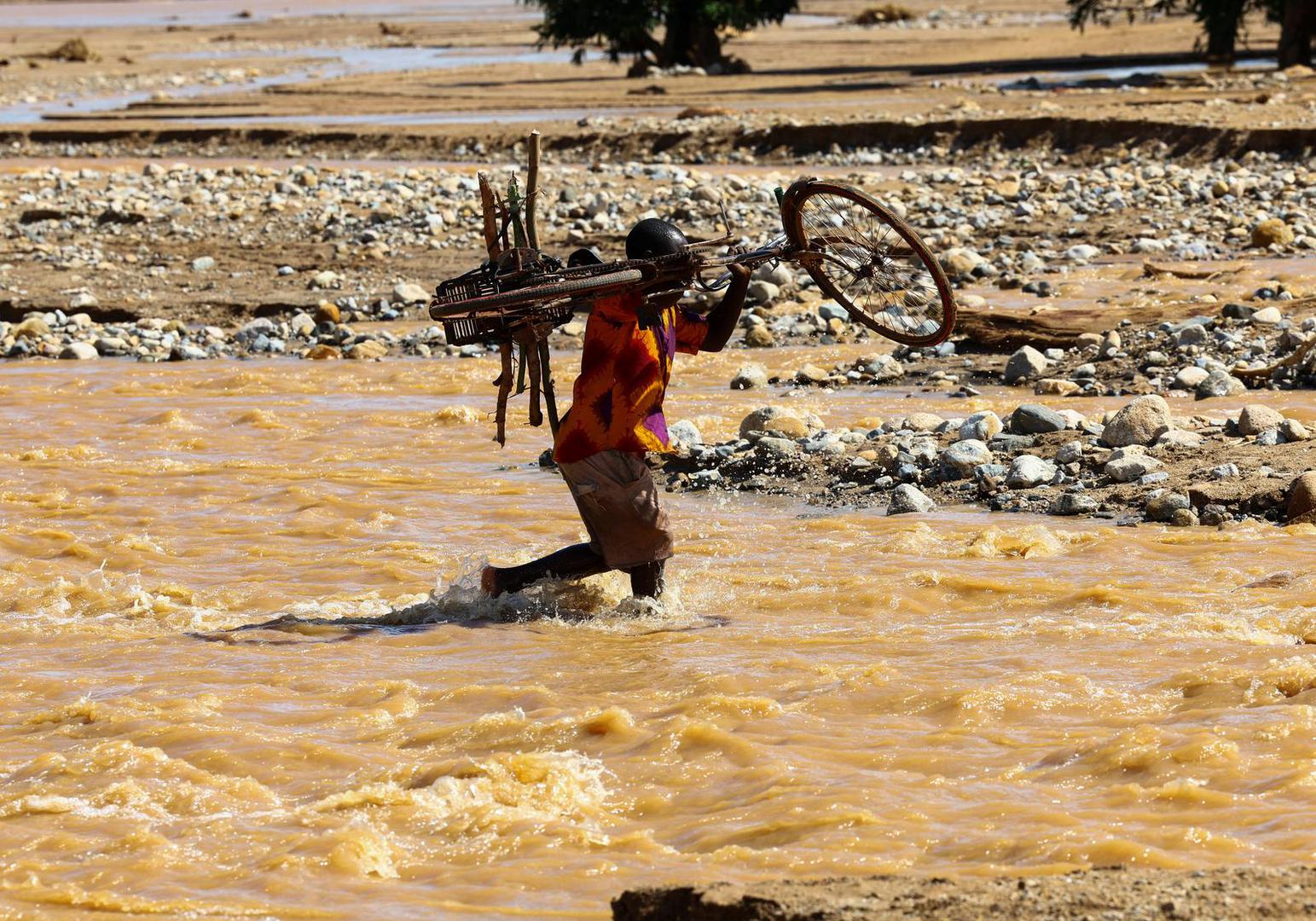 A man carries his bicycle over a flooded area in Muloza on the border with Mozambique after the tropical Cyclone Freddy, around 100 km outside Blantyre, Malawi, March 18, 2023. REUTERS/Esa Alexander Photo: ESA ALEXANDER/REUTERS