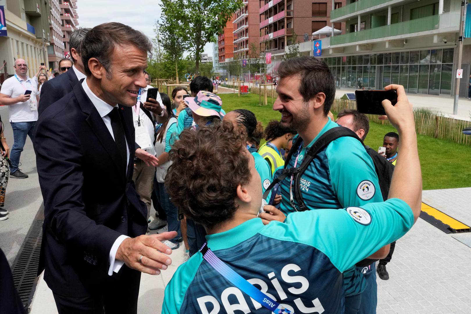 French President Emmanuel Macron poses for a selfie with volunteers as he visits the Olympic village for the 2024 Summer Olympics, in Paris, France, July 22, 2024.     Michel Euler/Pool via REUTERS Photo: MICHEL EULER/REUTERS