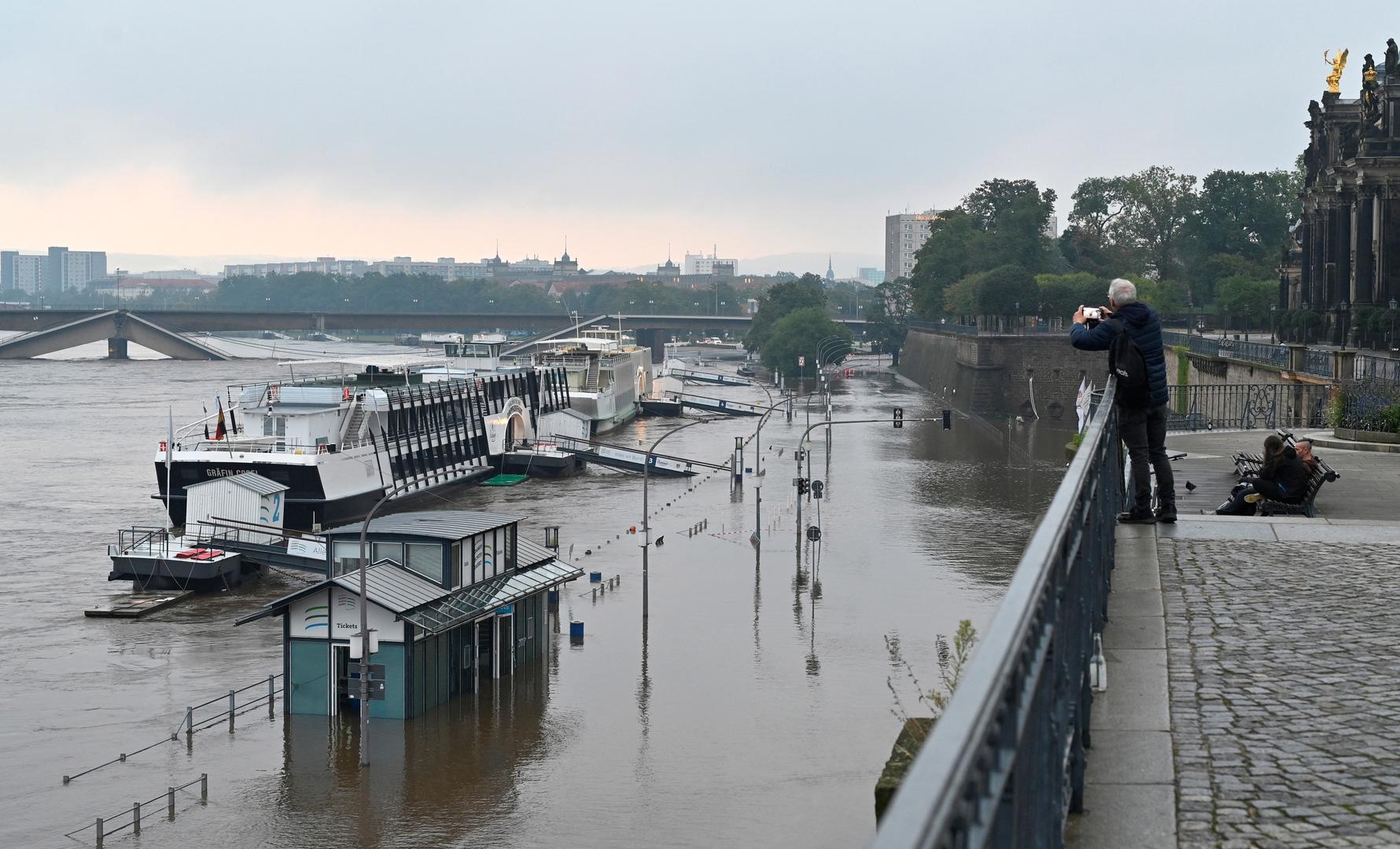 A man uses his phone as he views the flooding Elbe river near the partially collapsed Carola Bridge (Carolabruecke) in Dresden, Germany September 17, 2024. REUTERS/Matthias Rietschel Photo: MATTHIAS RIETSCHEL/REUTERS