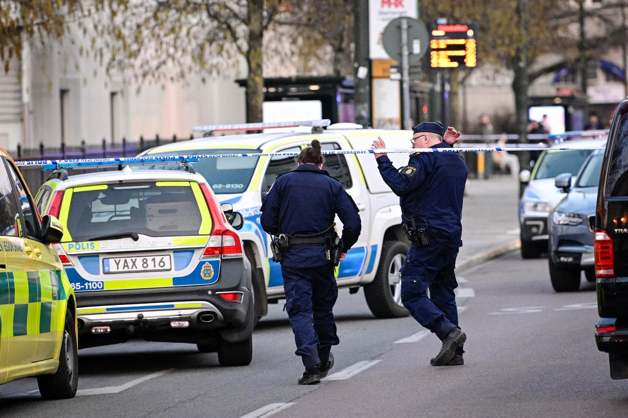 Police officers walk at the scene of a crime by a school in Malmo