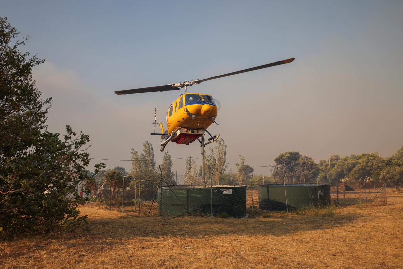 A firefighting helicopter resupplies water as a wildfire burns in Penteli, Greece, August 12, 2024. REUTERS/Stelios Misinas Photo: STELIOS MISINAS/REUTERS