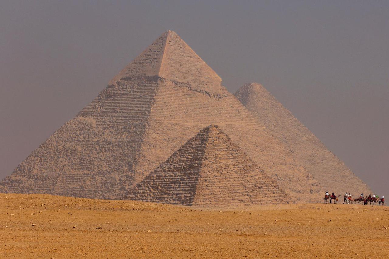 Tourists ride camels in front of the Great Pyramid of Giza, on the outskirts of Cairo