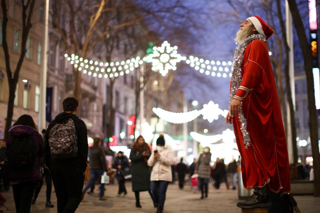 A man dressed as Santa Claus stands as lights illuminate a street as part of Christmas holiday season decorations in Vienna