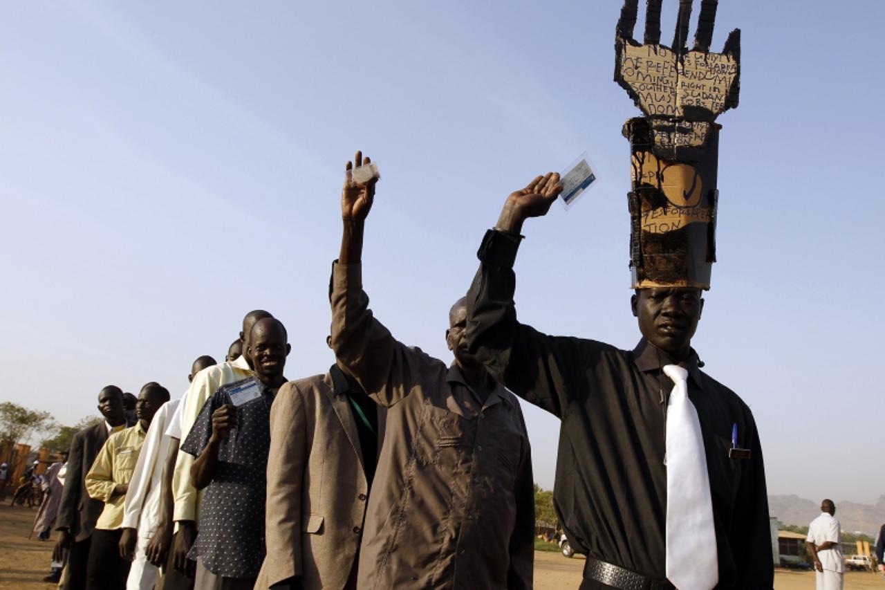 'South Sudanese men hold voters registration cards as they wait in line to vote at a polling station during the referendum in Juba, south Sudan January 9, 2011.  REUTERS/Goran Tomasevic  (SUDAN - Tags