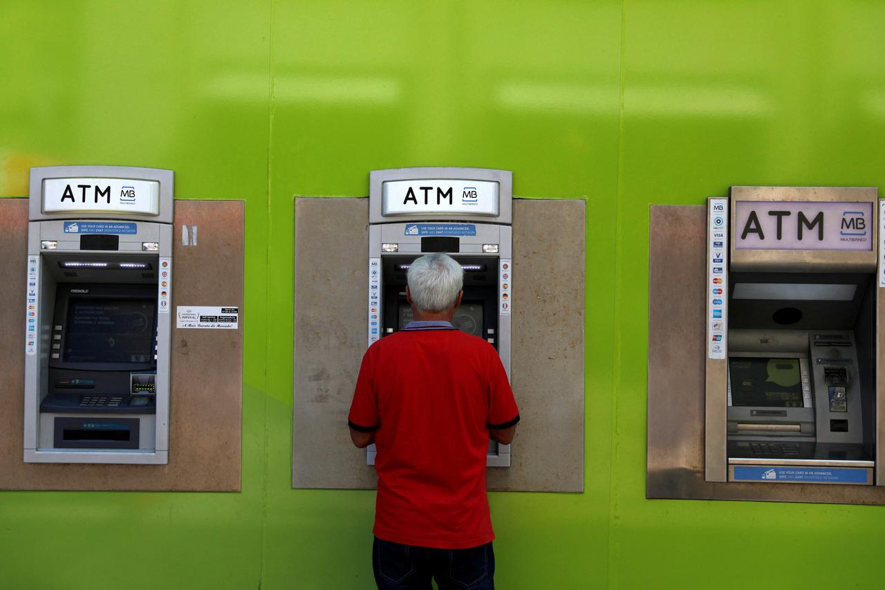 FILE PHOTO: A man uses an ATM at a Novo Banco branch in downtown Lisbon