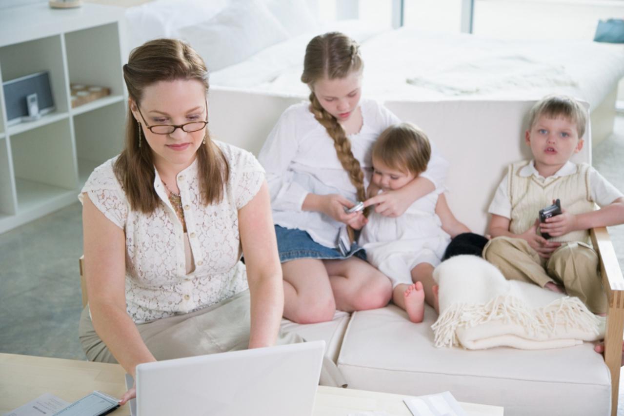 'Mother using laptop computer with children nearby'