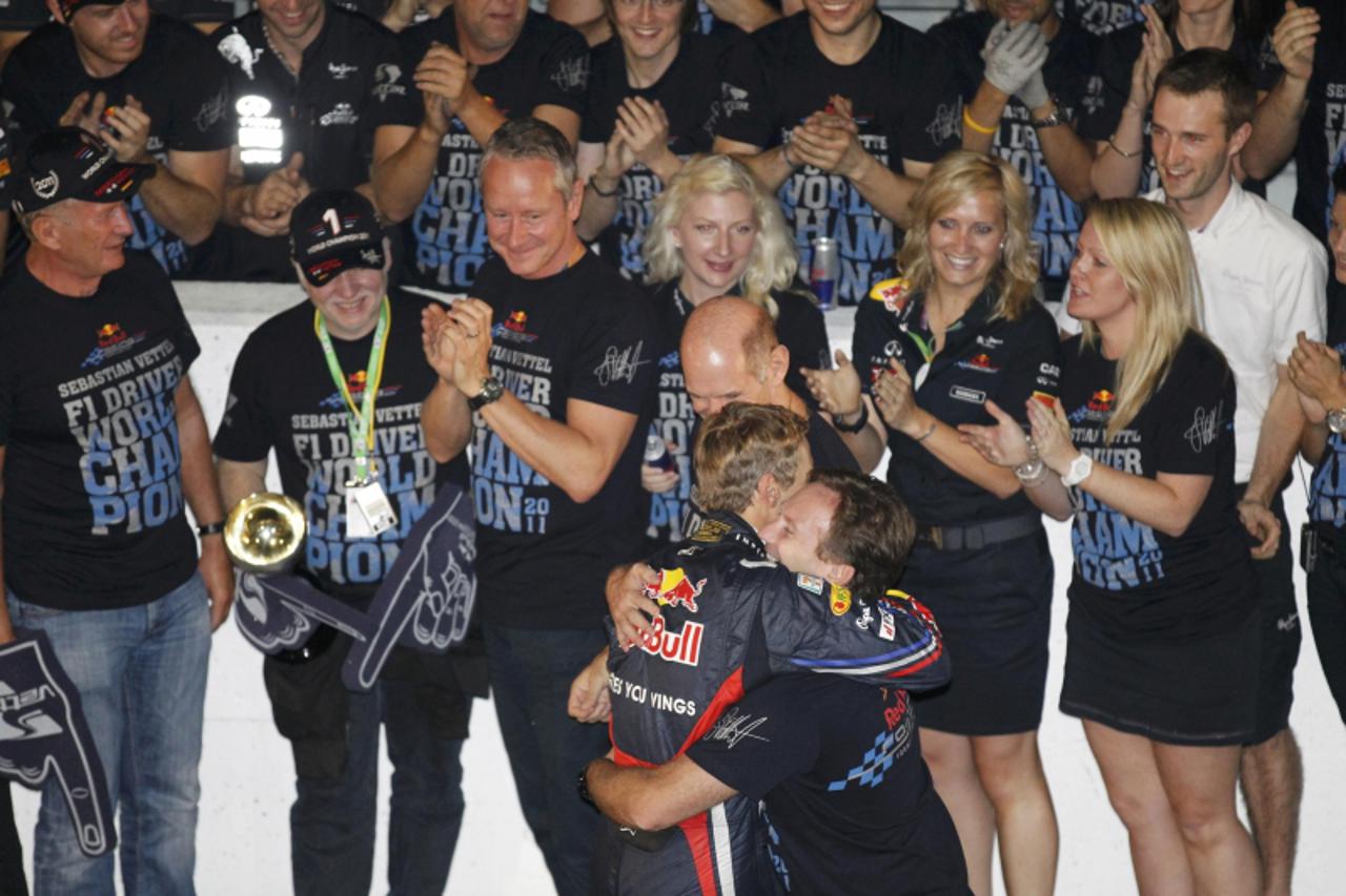 \'Red Bull Formula One driver Sebastian Vettel of Germany (C) hugs team principal Christian Horner as he celebrates with crew members winning the world championship after finishing third in the Japane