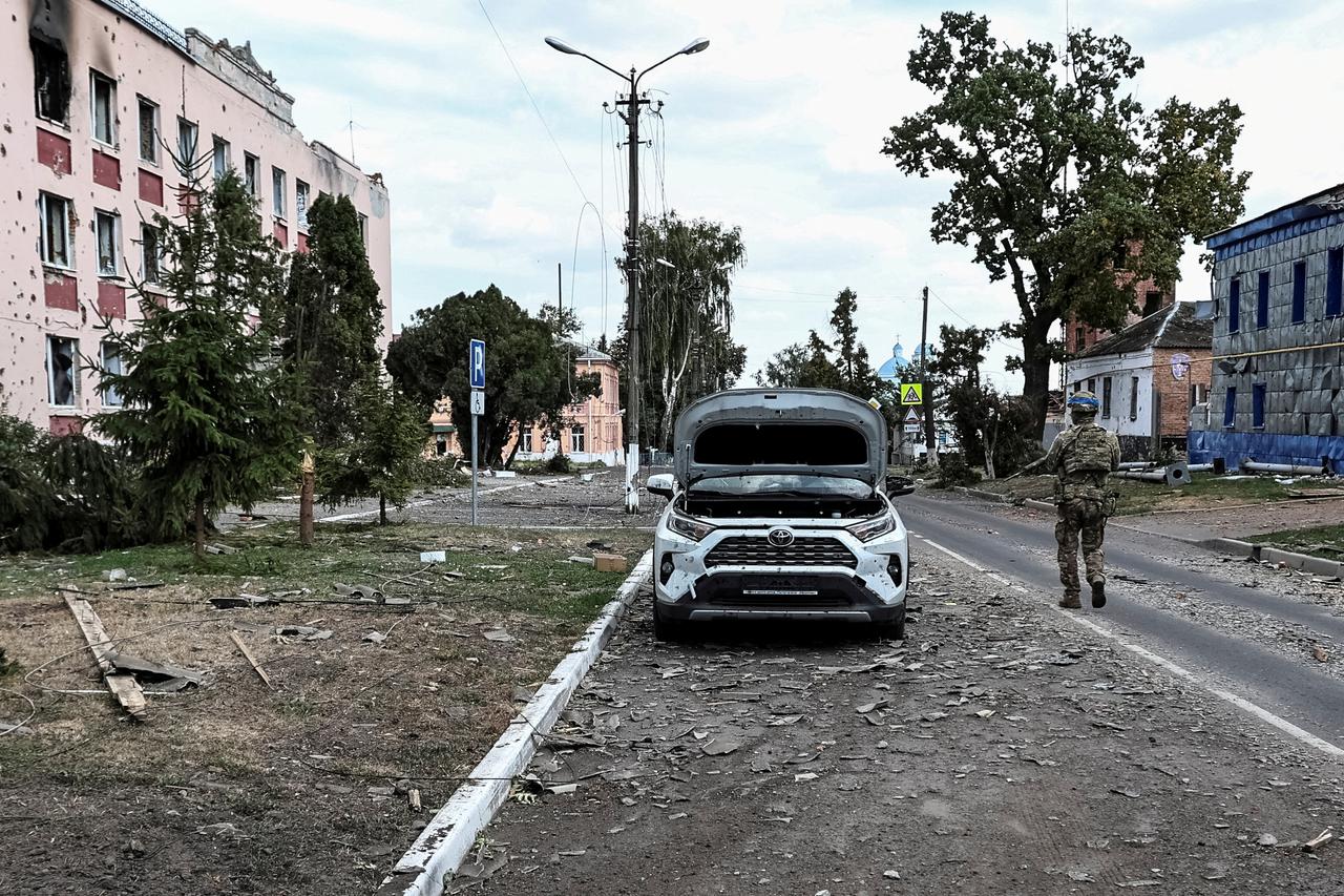 FILE PHOTO: A Ukrainian serviceman patrols a street next to damaged buildings in the town of Sudzha