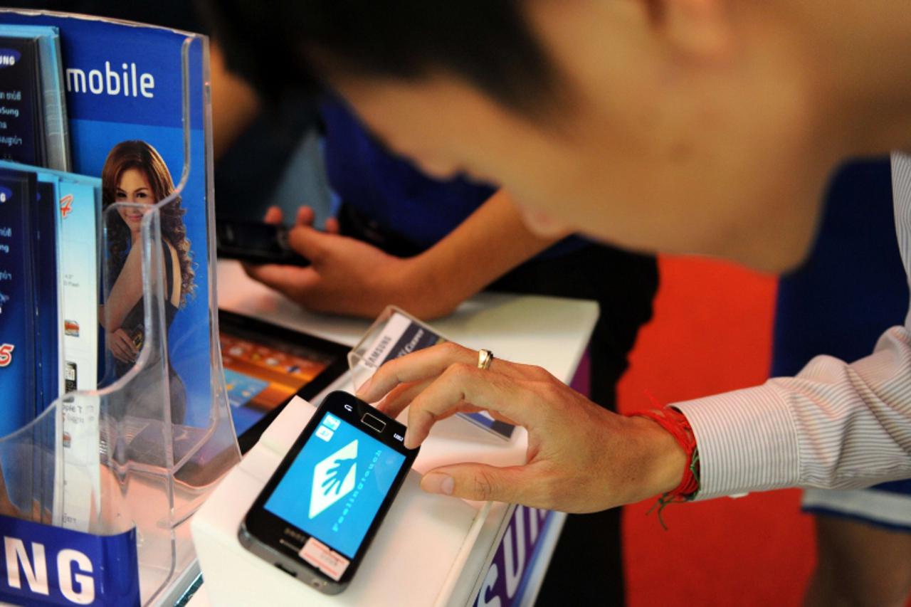 'A Cambodian man inspects the Samsung galaxy cooper during a promotional sale at a shop in Phnom Penh on October 21, 2011. South Korea\'s Samsung Electronics, the world\'s second-largest mobile phone 