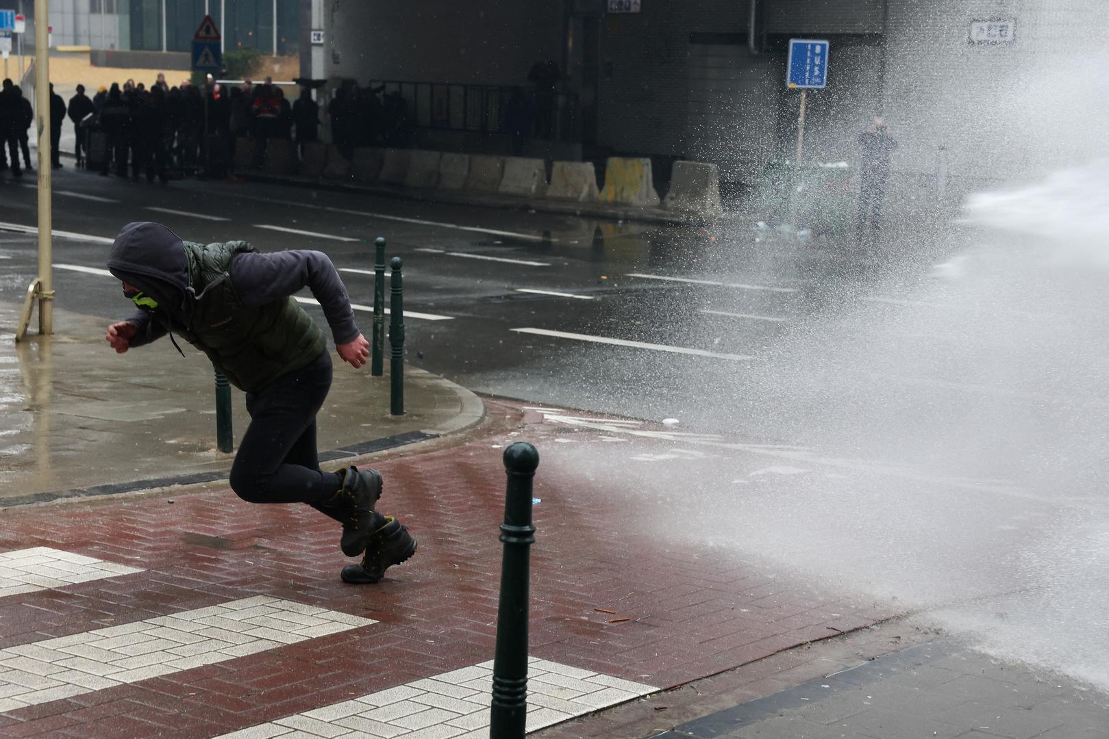 A man runs as water is sprayed during a protest of European farmers over price pressures, taxes and green regulation, on the day of an EU Agriculture Ministers meeting in Brussels, Belgium February 26, 2024. REUTERS/Yves Herman Photo: YVES HERMAN/REUTERS