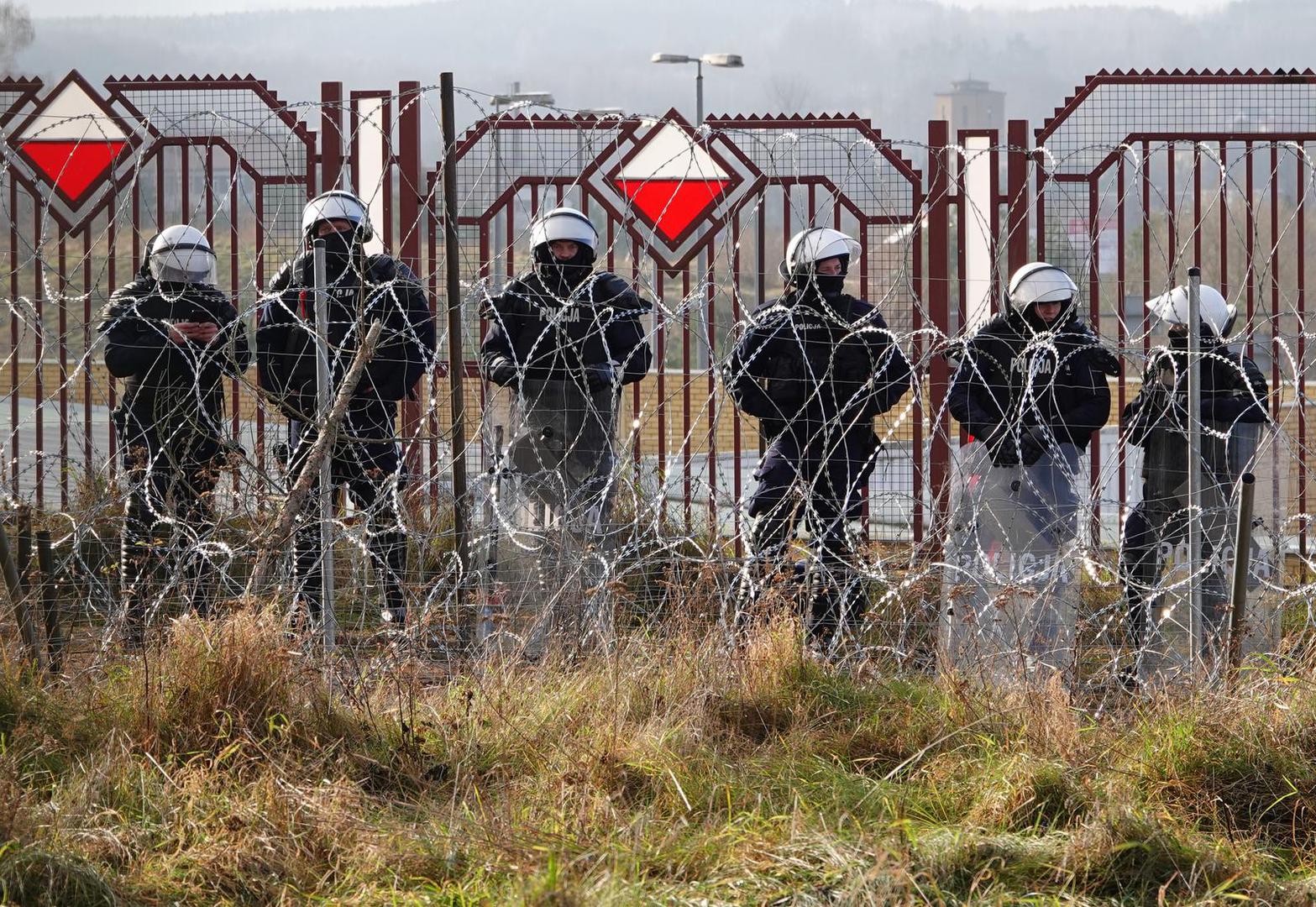 18 November 2021, Belarus, Brusgi: Polish security forces stand behind barbed wire at the border. Photo: Ulf Mauder/dpa