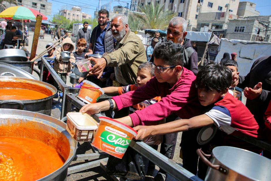 FILE PHOTO: Palestinians wait to receive food cooked by a charity kitchen, in Rafah, in the southern Gaza Strip