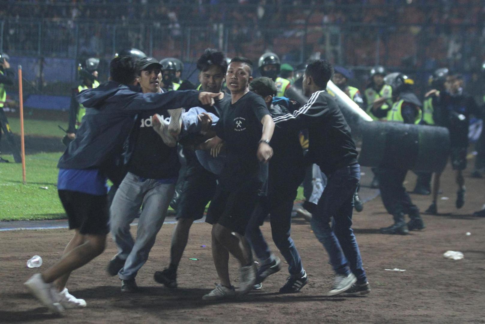 Supporters evacuate a man hit by tear gas fired by police during the riot after the league BRI Liga 1 football match between Arema vs Persebaya at Kanjuruhan Stadium, Malang, East Java province, Indonesia, October 2, 2022, in this photo taken by Antara Foto. Antara Foto/Ari Bowo Sucipto/via REUTERS    ATTENTION EDITORS - THIS IMAGE HAS BEEN SUPPLIED BY A THIRD PARTY. MANDATORY CREDIT. INDONESIA OUT. NO COMMERCIAL OR EDITORIAL SALES IN INDONESIA. Photo: ANTARA FOTO/REUTERS