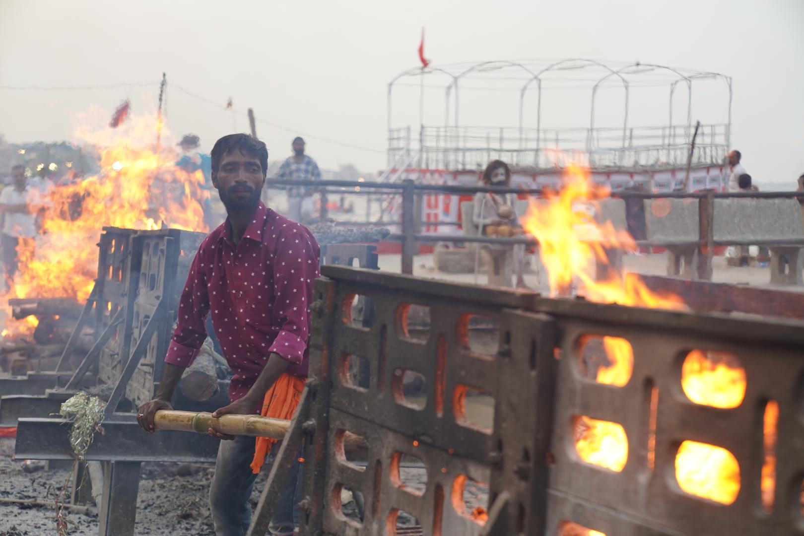 20 July 2024, India, Varanasi: A man burns corpses by the Ganges. It is so hot there that his eyes water. Photo: Anne-Sophie Galli/dpa Photo: Anne-Sophie Galli/DPA