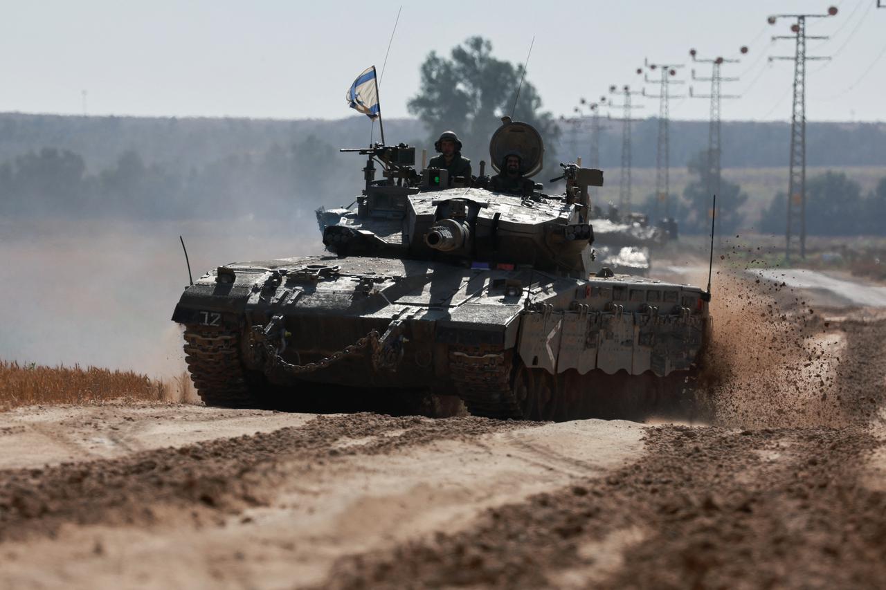 Israeli soldiers gesture in a tank, amid the ongoing conflict between Israel and the Palestinian Islamist group Hamas, near the Israel-Gaza Border