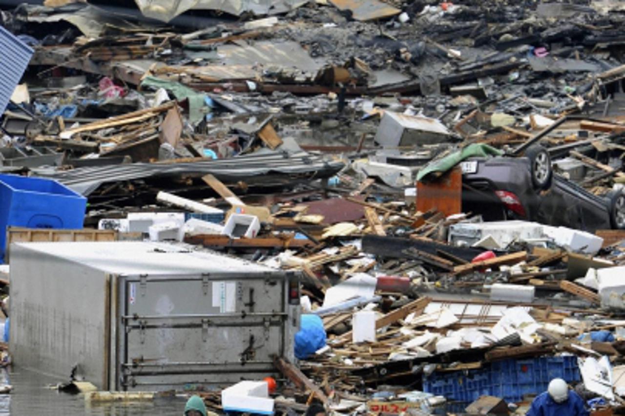 'People use a floating container to escape from floodwaters after a tsunami and earthquake in Kesennuma City, Miyagi Prefecture in northeastern Japan March 12, 2011. Japan confronted devastation along