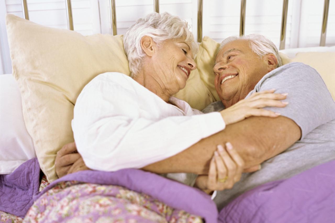 \'High angle view of a senior couple lying on the bed, hugging\'