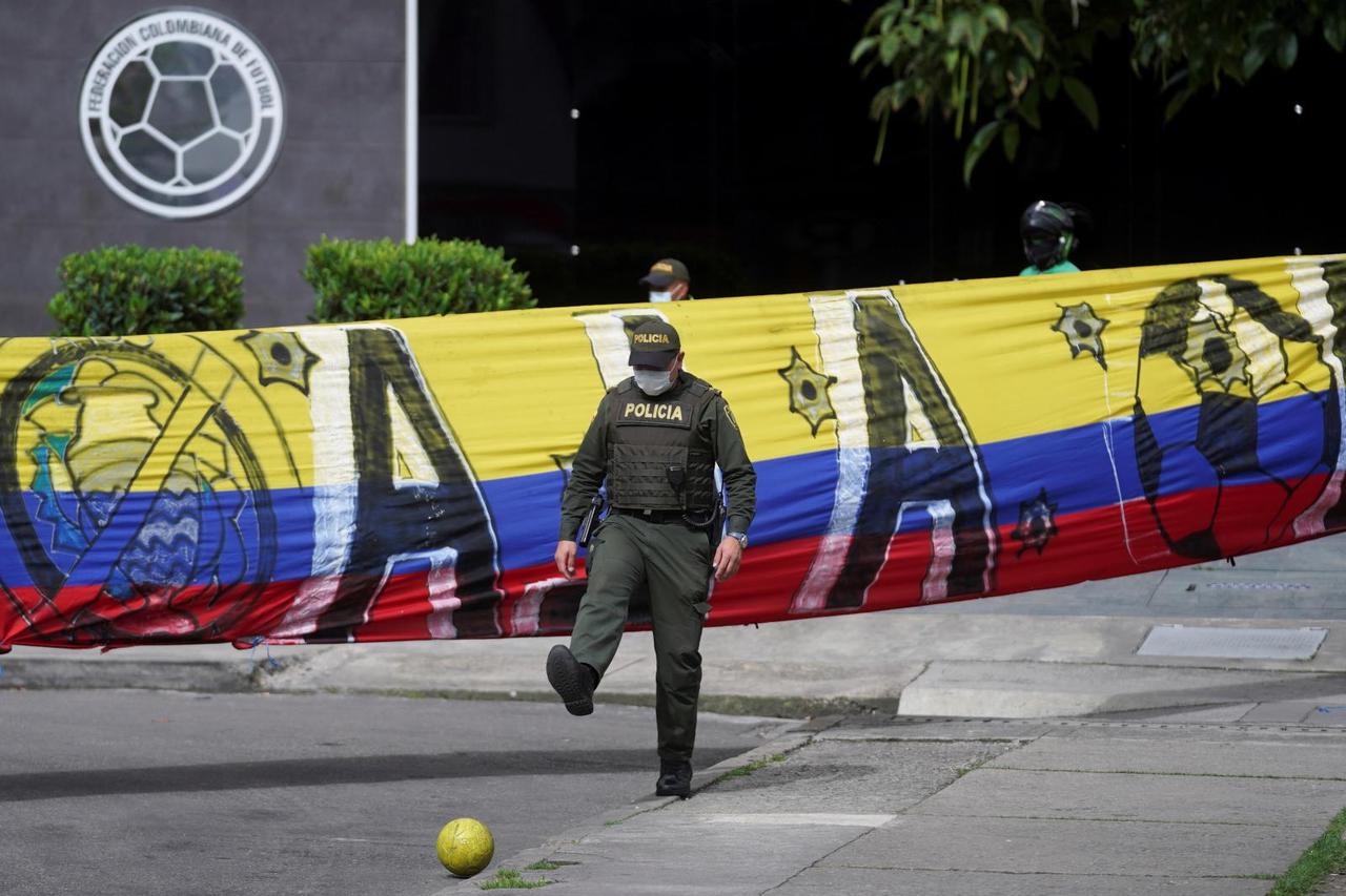 A police officer kicks a ball as soccer fans (not pictured) stage a sit-in, in front of the Colombian Football Federation (FCF), in Bogota