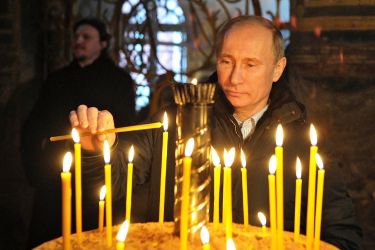 \'Russia\'s Prime Minister Vladimir Putin lights a candle as he visits the Bogorodichny Uspensky Monastery in the town of Tikhvin, some 170 km, east of St. Petersburg, on January 30, 2012.  AFP PHOTO/