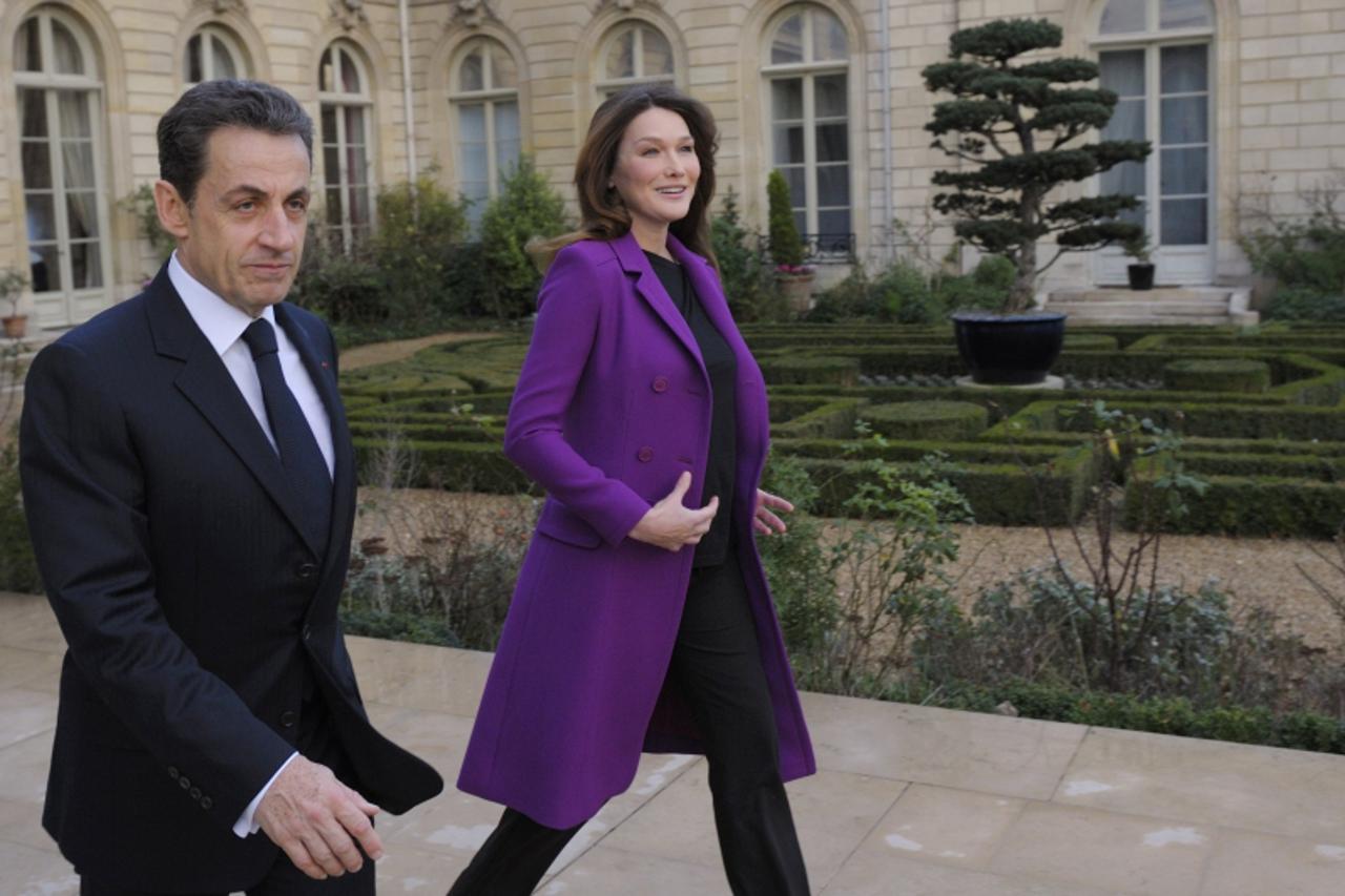 'France\'s President Nicolas Sarkozy and First Lady Carla Bruni-Sarkozy walk to greet Ivory Coast First Lady Dominique Ouattara (not pictured) at the Elysee Palace in Paris, January 26, 2012. Ivory Co